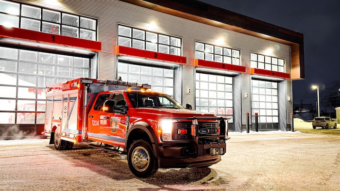 Un camion de pompiers devant une caserne.