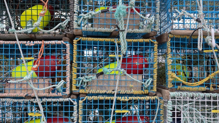 Des casiers à homard empilés et entourés de cordages.