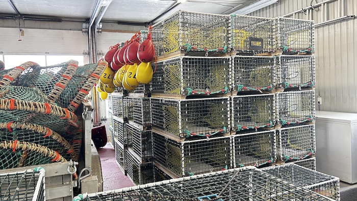 Des cages à homard empillées dans un entrepôt.