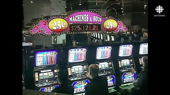 Plusieurs machines à sous avec des joueurs assis devant.