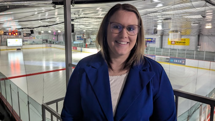 Cassandra Woodberry sourit à la caméra en prenant la pose devant une patinoire.