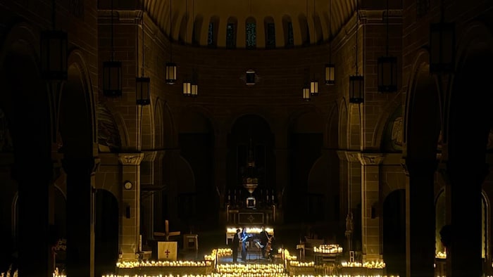 Des musiciens se produisent en concert à l'intérieur de la cathédrale, illuminée aux chandelles.