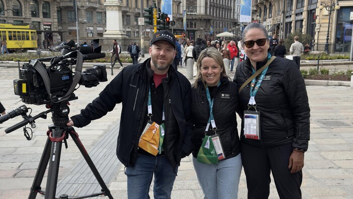 Trois personnes posent avec une caméra de télévision dans un espace public de Milan.