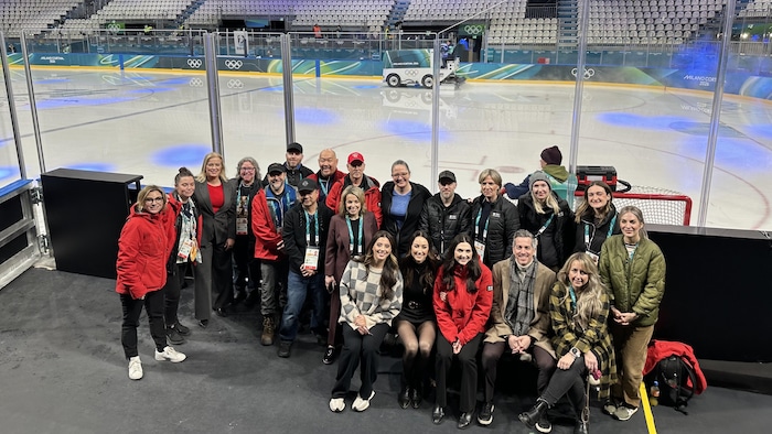 Un groupe de techniciens et journalistes près d'une patinoire.