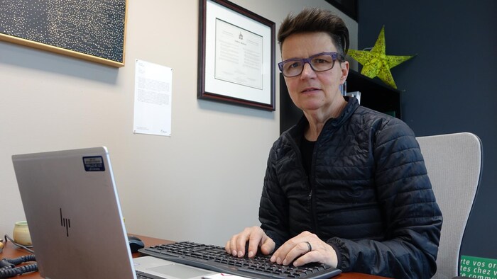 Catherine McKenney pose pour une photo devant un ordinateur dans un bureau.