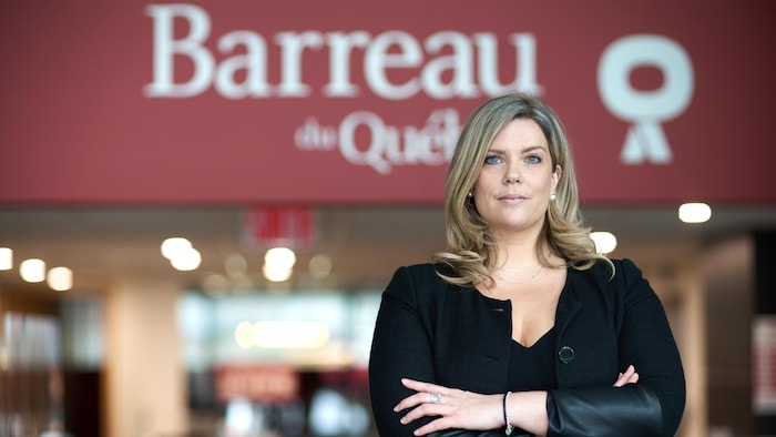 Une femme se tient devant l'entrée de l'édifice du Barreau du Québec.   
