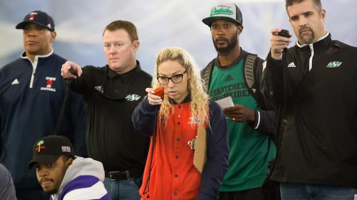 Une femme en rouge entouré d'hommes pendant une séance d'entraînement. 