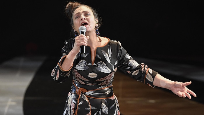 Une femme chante sur scène. 