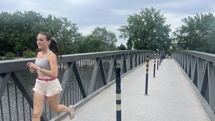 Une jeune femme athlétique tribunal  sur un pont au-dessus du canal Lachine.