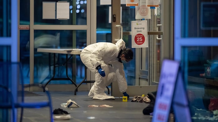 Un expert en scènes de crime ramasse des preuves à l'intérieur de la bibliothèque de Lynn Valley, à North Vancouver, après l'attaque à l'arme blanche survenue le samedi 27 mars 2021.