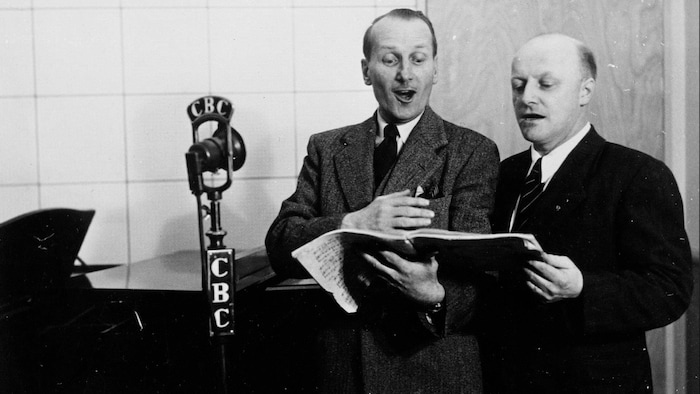 Vilmond Fortin et un autre homme chante derrière un micro en studio.