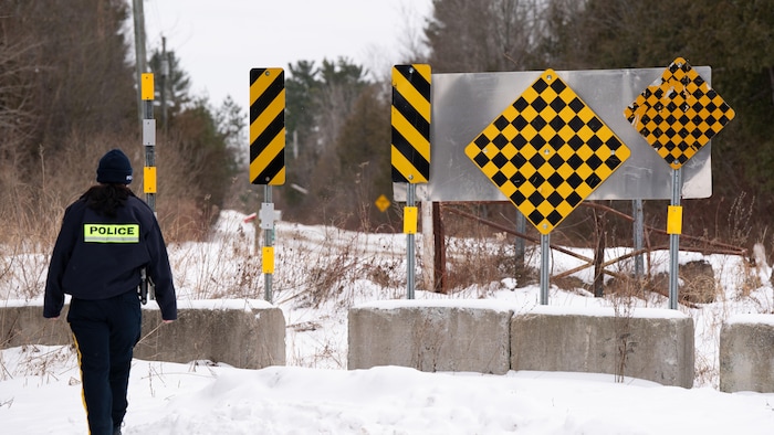 Un agent de la GRC marche dans la neige sur un chemin boisé. 