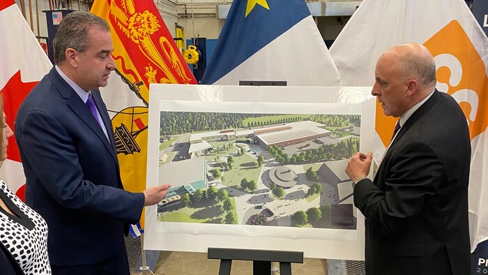 Deux hommes discutent en regardant le plan d'un nouveau bâtiment. 