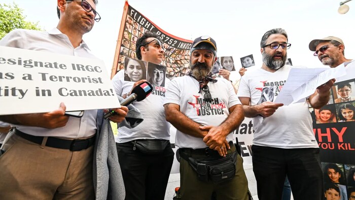 Mehrzad Zarei, centre, listens as his letter for Prime Minister Justin Trudeau is read aloud by a fellow protester, second from right in Ottawa on Thursday, Aug. 25, 2022. Zarei is the father of one of the 176 passengers killed onboard a Ukraine International Airlines Flight PS752 crash and marched from Richmond Hill, Ont. to downtown Ottawa in hopes that Prime Minister Justin Trudeau will meet with the families of victims. (Spencer Colby/The Canadian Press)