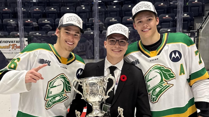 Cédrik Cabana avec deux joueurs des Knights de London et le trophée.