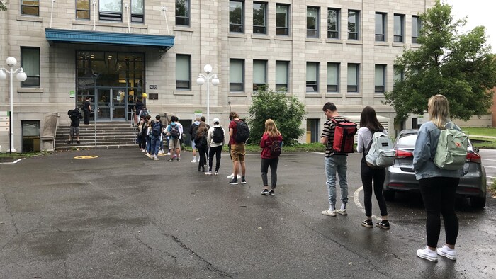 Des étudiants font la file devant la porte du cégep.