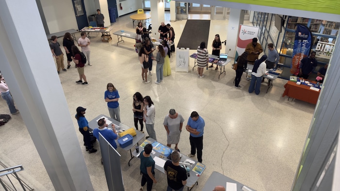 Des kiosques et plusieurs personnes debout dans le hall d'entrée du cégep.