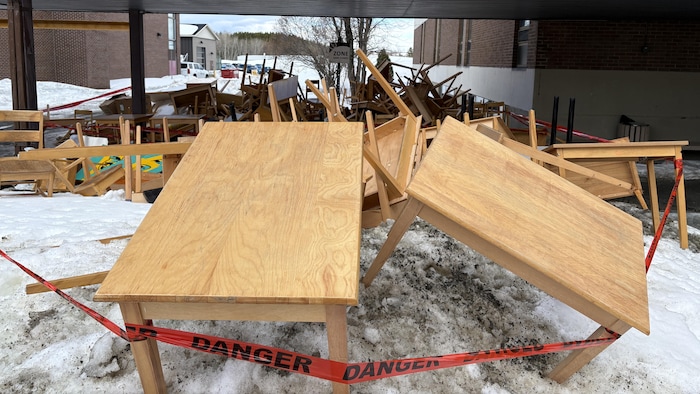 Des tables et des chaises de bois jetés dans la neige.