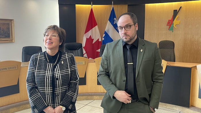 Céline Brindamour et Benjamin Turcotte, debout dans la salle du conseil municipal, répondent aux questions des journalistes.