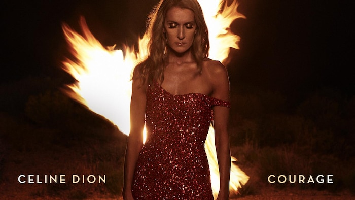 Céline Dion a les yeux fermés et se tient devant la flamme d'un feu de camp à l'extérieur. 