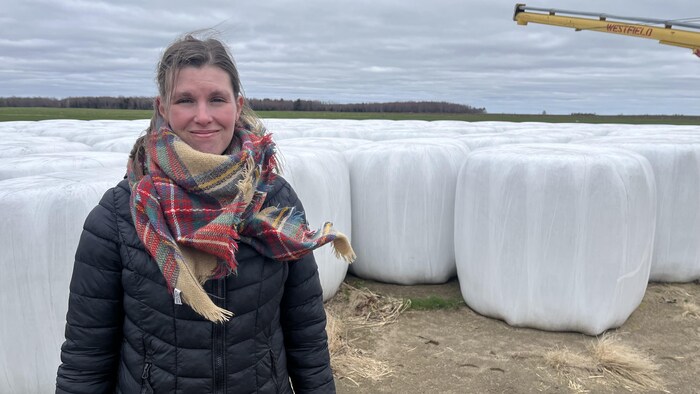 Céline Dumas devant des balles de foin ensilées.