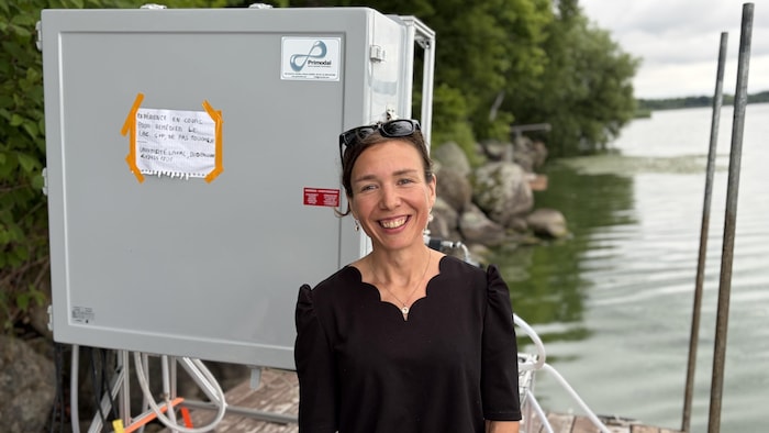 La chercheuse pose devant sa mini-usine de filtration aux abords du lac.