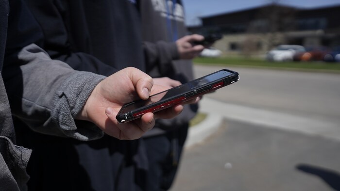 Des jeunes avec des cellulaires dans la main.