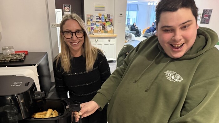 Deux personnes dans une cuisine utilisent un air fryer.