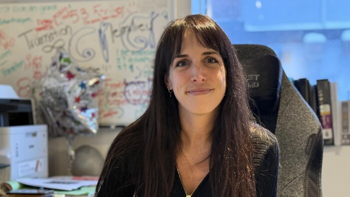 Une femme sourit à la caméra.