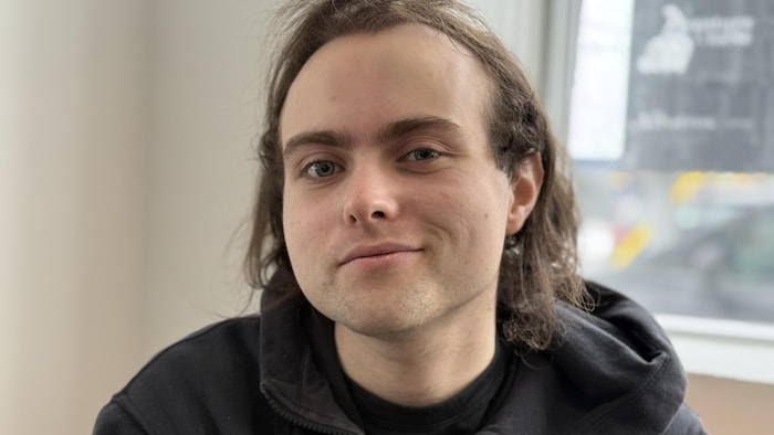 Un homme regarde la caméra, sourire en coin.