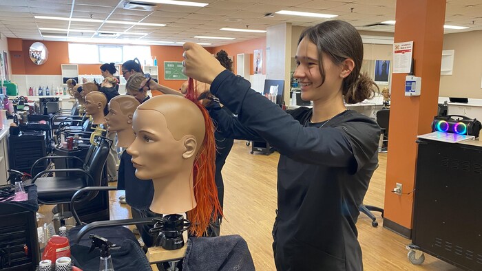 Des étudiants en coiffure se pratiquent sur des mannequins. 