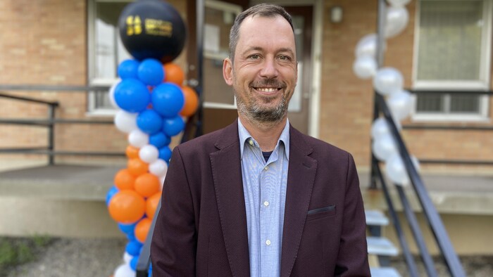 Michel Alexandre Cauchon pose devant ballons posés devant une entrée.