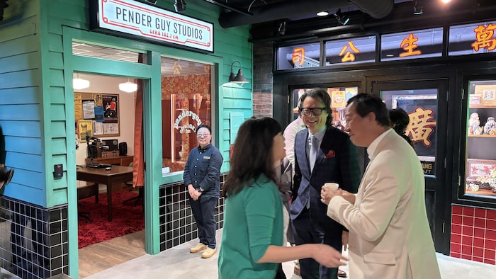 Des gens se parlent devant l'enseigne d'un studio de radio.