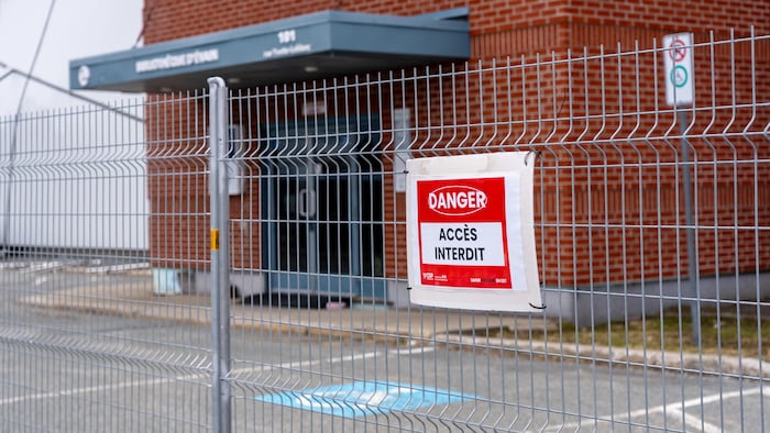 Un panneau sur une clôture indique que l'accès au bâtiment est interdit.