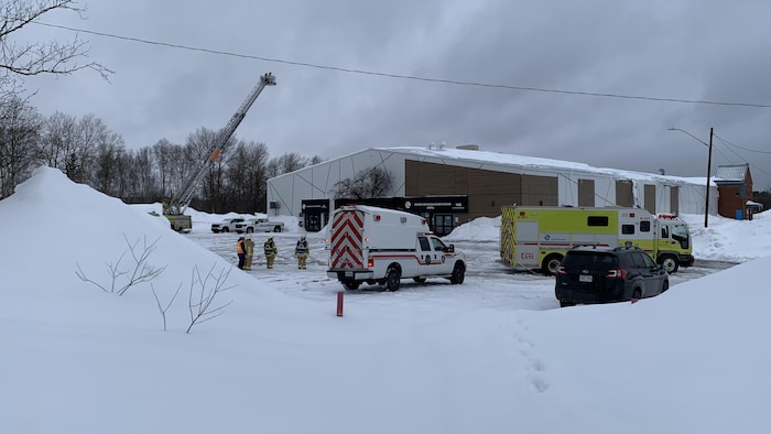 Une grue et des camions de pompiers devant le Centre communautaire d'Évain.