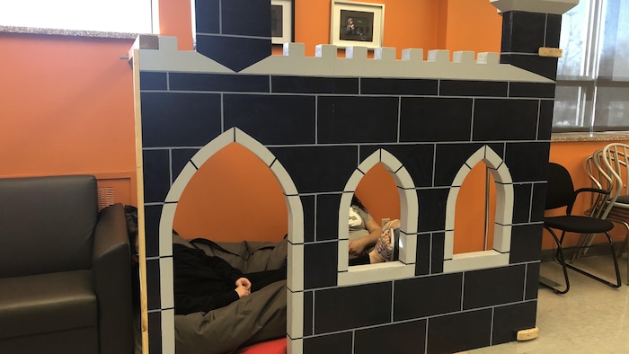 Deux jeunes cachées dans une construction en forme de château dans une salle du centre.