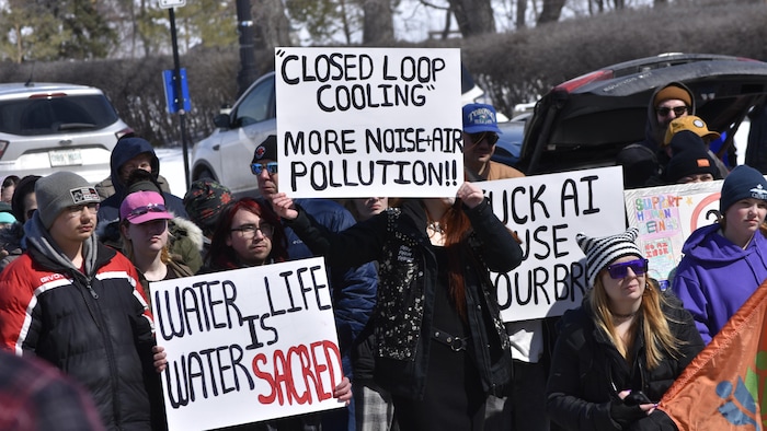 Des manifestants par temps froid, brandissant des pancartes avec des slogans exprimant leur opposition à un centre de données à cause de la pollution de l'eau et du bruit.