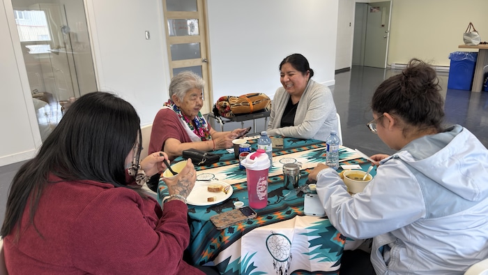 Quatre femmes partageant un repas. 