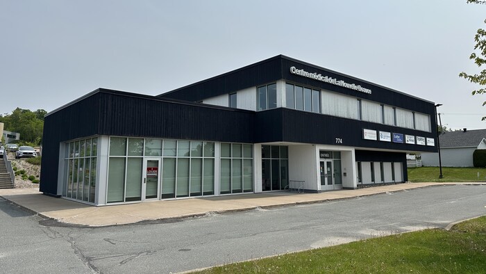 Un édifice commercial bleu et blanc avec un stationnement désert.