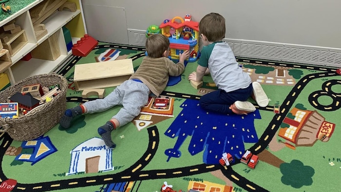 Deux enfants en bas âge jouent avec des jouets sur le sol de la garderie.
