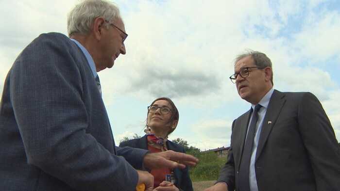 Trois personnes discutent à l'extérieur.