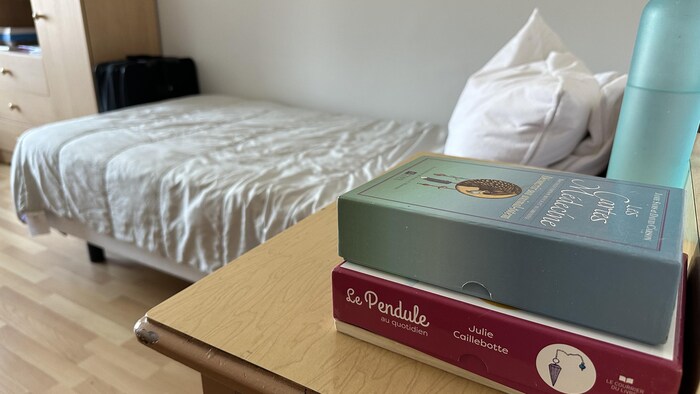 Des boîtes de pensées méditatives et une gourde d’eau sont déposées sur une table de chevet à côté d’un lit.
