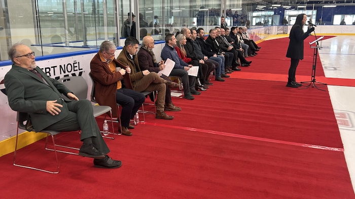 De nombreux dignitaires assis sur des chaises disposées sur un tapis rouge. 