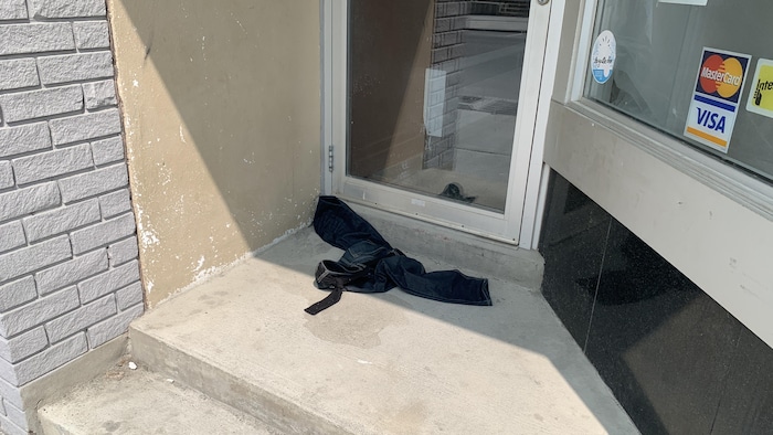 Une paire de jeans laissée à terre, devant la porte d'un commerce.