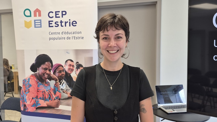 Isabelle Harnois devant une affiche du Centre d'éducation populaire (CEP) de l'Estrie.