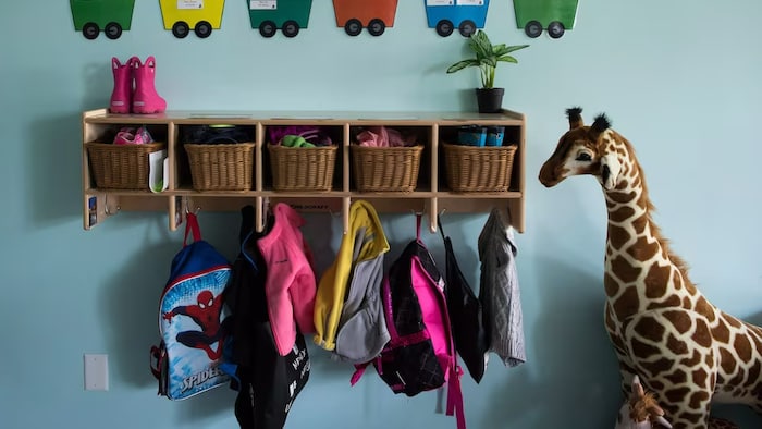 Crochets avec vêtements d'enfants et grande peluche de girafe.