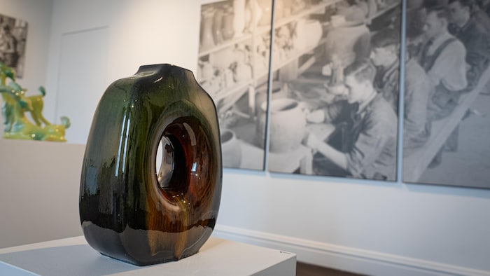 Une base de lampe dans un musée devant une photo géante d'ouvrier dans un atelier en noir et blanc.