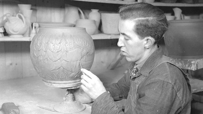 Un homme travaille sur un vase dans un atelier.