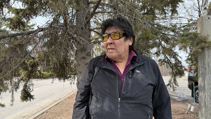 Peter Moonias devant un arbre.