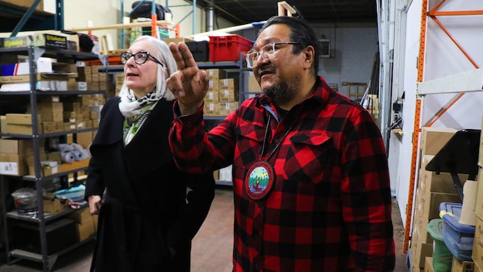 Bruce Achneepineskum et Patty Hajdu marchent dans un entrepôt.